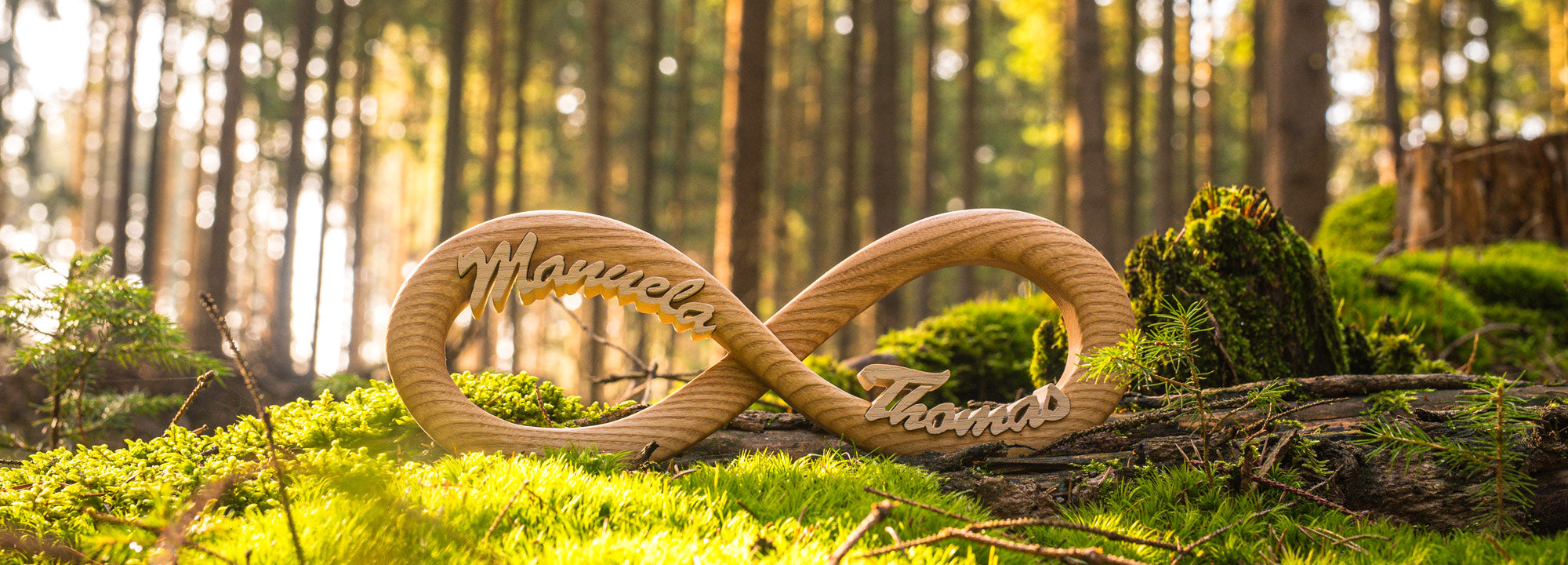 Handgefertigte Holz-Endlosschleife mit den Namen Manuela und Thomas, fotografiert im Vogtländer Wald — MIAT Holz Design
