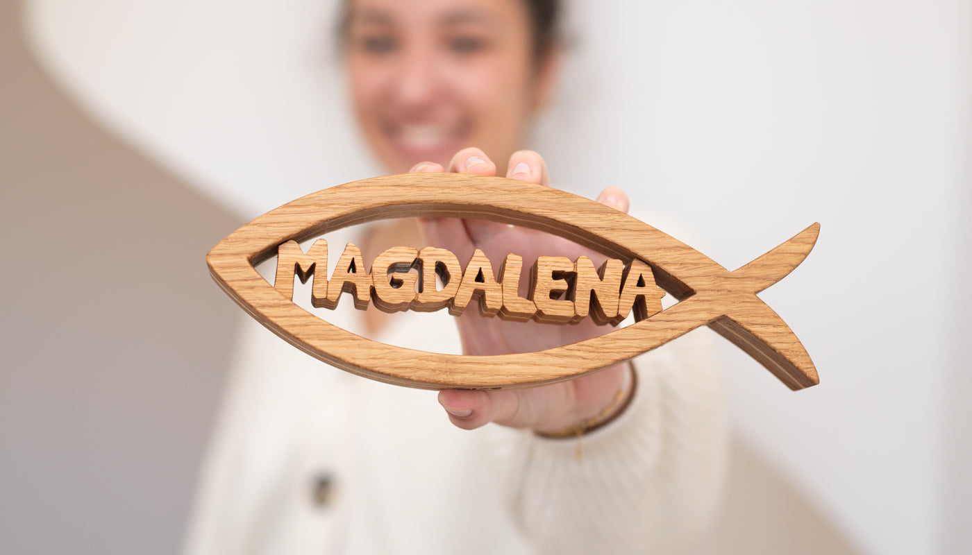 Personalisierter Holz-Christusfisch aus Eiche als Taufgeschenk, in einer Hand gehalten – handgefertigt von MIAT Holz Design.